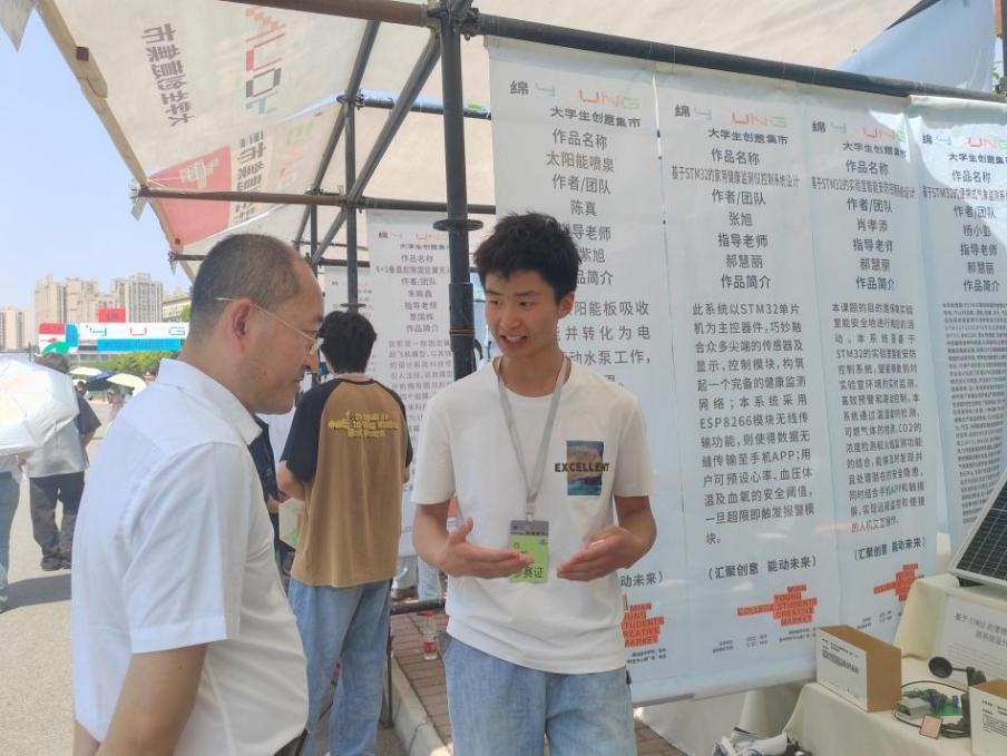 说明: 8-2 创意集市上同学在展示便携式气象仪及智能救援头盔